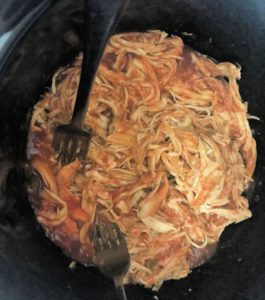 Use two forks to shred the chicken in the slow cooker.